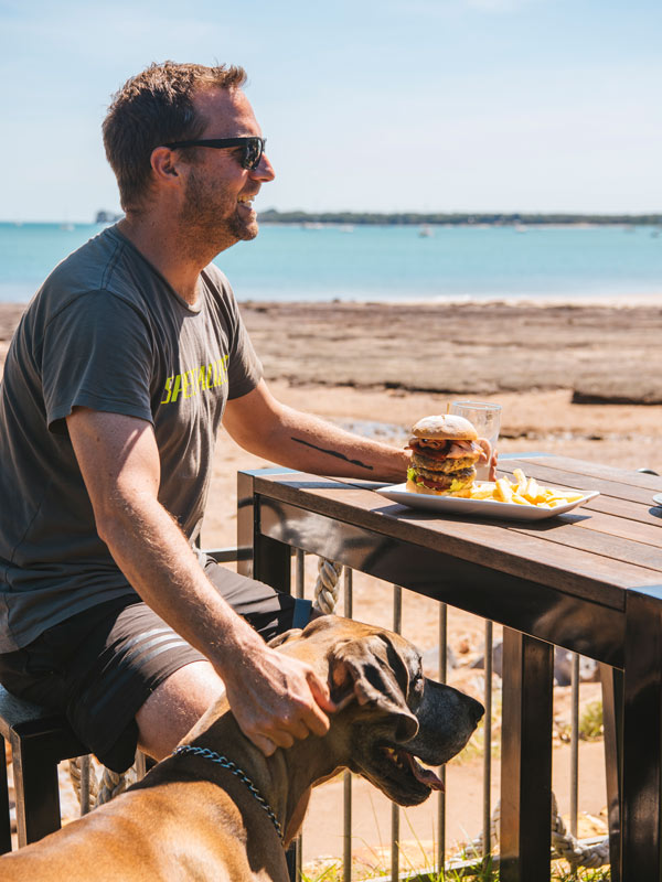Man and his dog with a huge burger and chips from Epikur at Darwin Ski Club. 