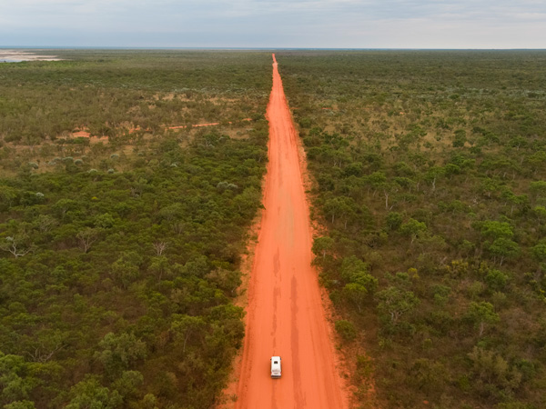 an aerial view of a vehicle driving along the red dirt on Gibb River Rd