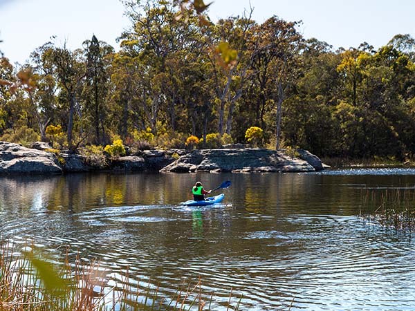 Woman enjoying an afternoon kayak through Ganguddy (Dunns Swamp) in Wollemi National Park, Mudgee, NSW, Australia