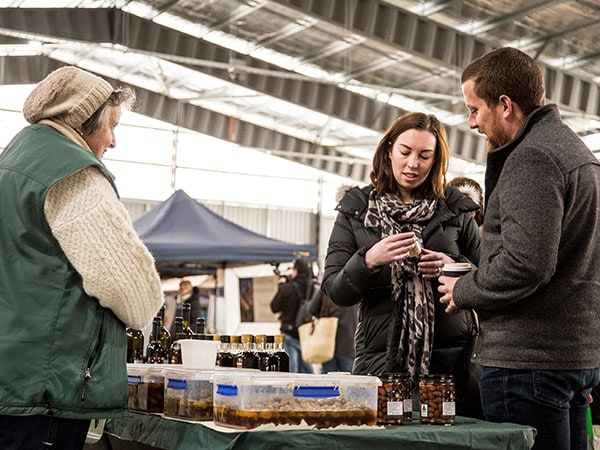 Couple enjoying food tastings from local farms at the Orange Farmers Market, Orange, NSW, Australia