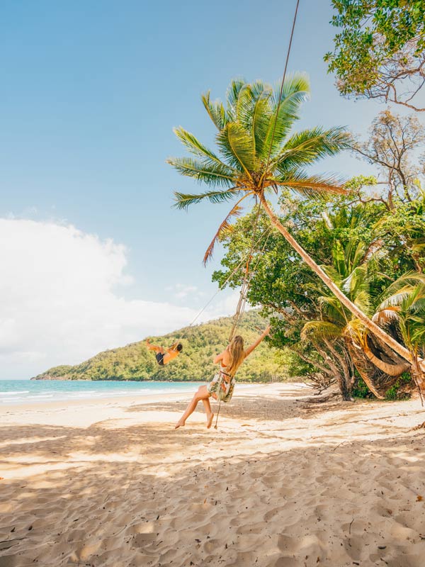 Mother and child swinging on rope swing Cape Tribulation beach. (Image: Tourism and Events Queensland)