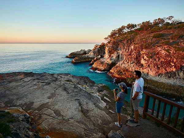 A couple watching the sunset over the ocean at North Gorge walk on North Stradbroke Island.
