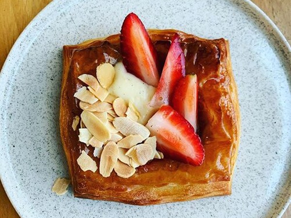 a pastry on a plate topped with nuts and strawberries at Black Cockatoo Bakery