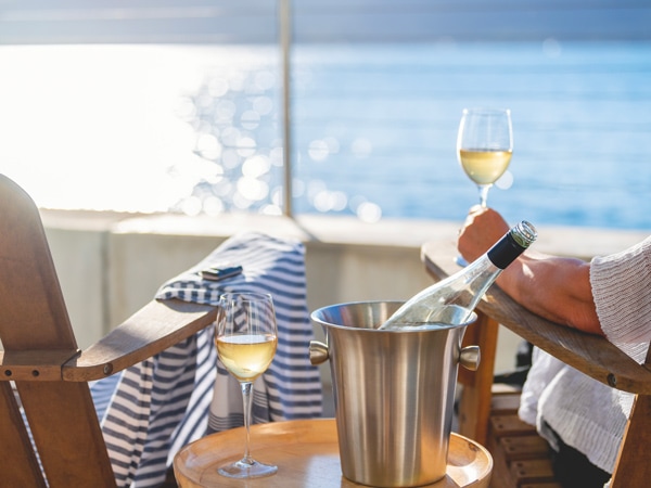 a woman sitting in a waterfront deck chair with a glass of wine
