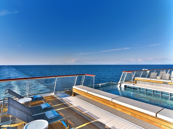 an infinity pool with lounge chairs facing the sea