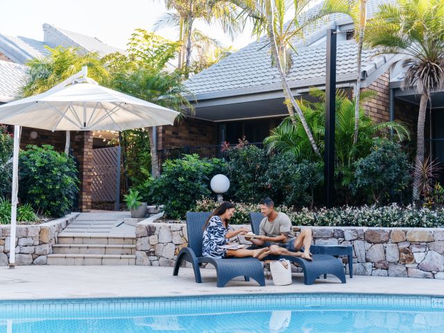a couple relaxing by the pool at Glen Eden Beach Resort, Sunshine Coast