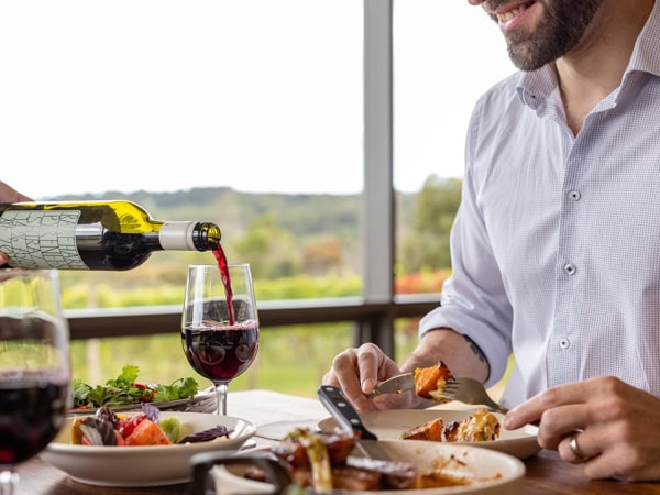pouring wine into a glass in front of a man sitting at Jackalope
