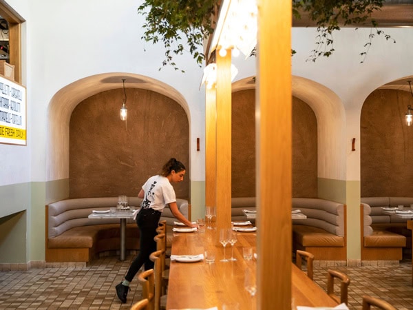 a female staff at Osteria Oggi arranging tables