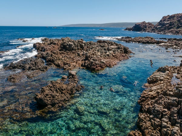 jumping off a cliffside rock into a coastal rock pool at Cape to Cape Track