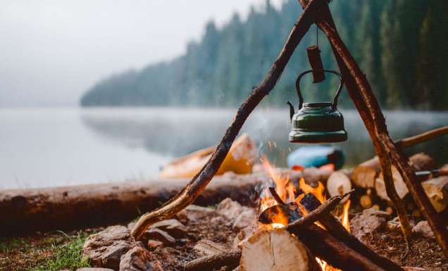 Campfire with a vintage kettle next to the beautiful lake.