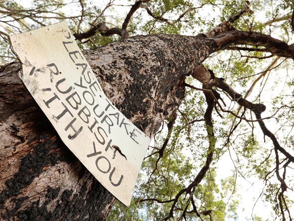 multiple views of an old worn sign post instructing campers fishermen bush walkers hikers to take responsibility for removing all waste trash rubbish and take it with them. Environmentally responible behaviour. warning sign no littering. Say no to illegal dumping concept story