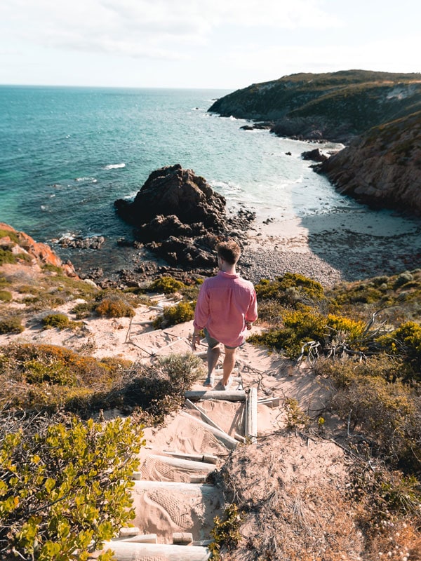 a man going down the cliff path to the beach at Walk the Yorke trail