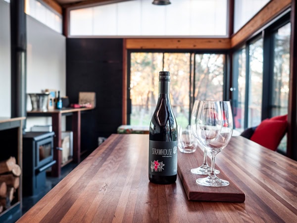 a bottle of wine alongside a empty glasses on the table inside Strawhouse Wines