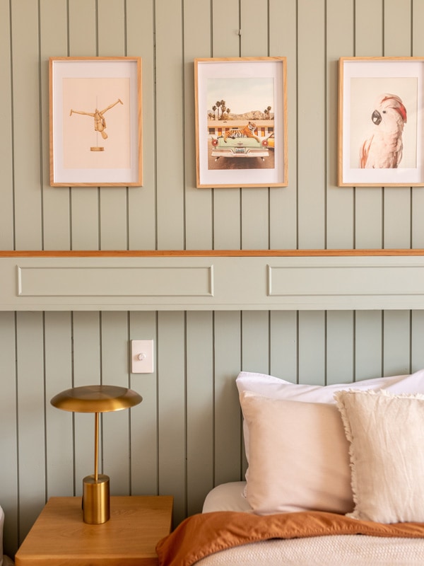Art hangs above the bed on the sage coloured wall.