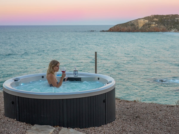 Woman drinking wine in the jacuzzi by the cliff. 
