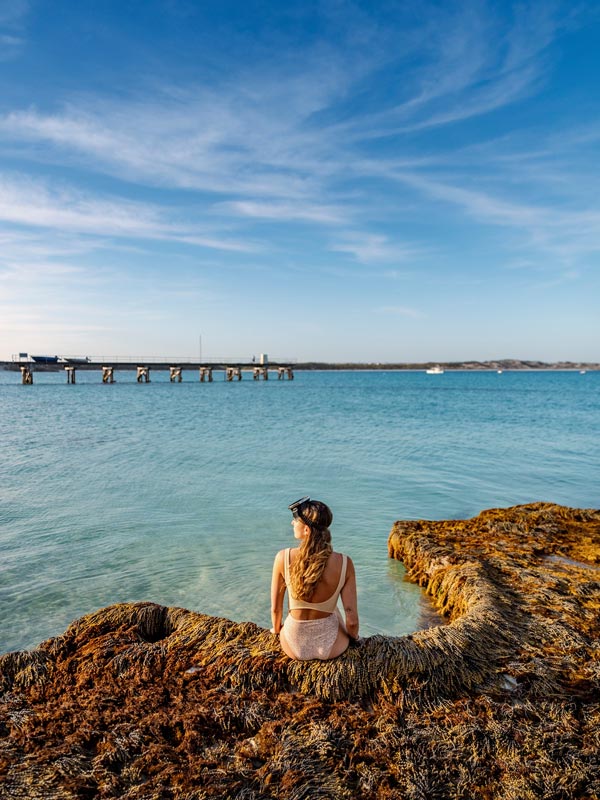 Woman sits on cliff face overlooking Vivonne Bay.