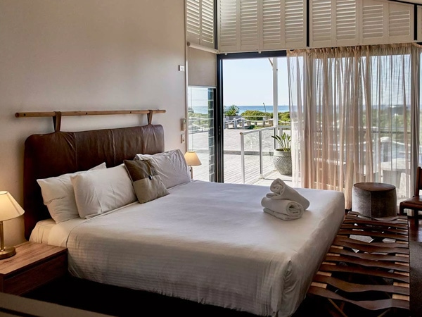 a bedroom with balcony at Caves Coastal Bar & Bungalows