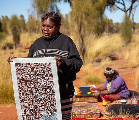 Women holding art work at Desert art at Maruku, Uluru