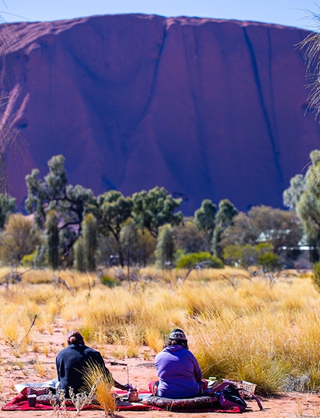 Women painting with Uluru in the background