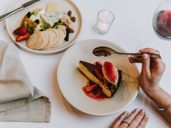 a hand holding a spoon to get a piece of cake at Commodore on the Park