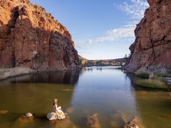a woman sitting on a rock at Glen Helen Gorge