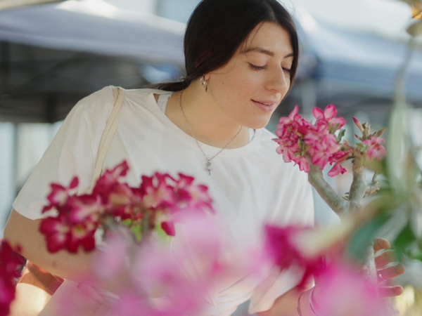 a woman smelling flowers at Nightcliff Markets