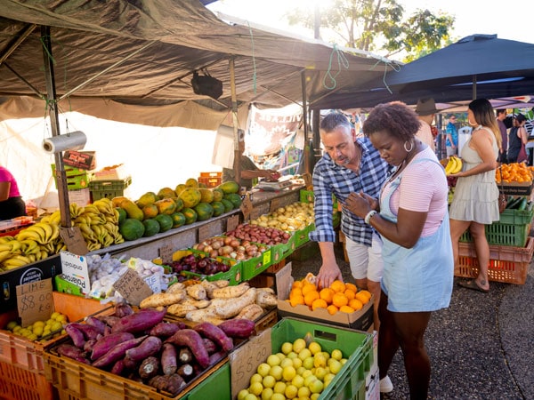 a couple checking out the fresh produce on display at a stall in Parap Village Markets