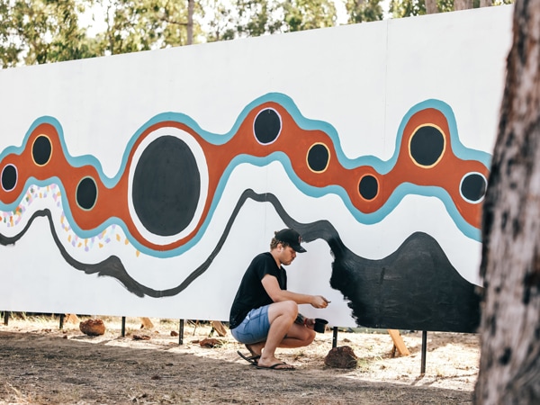 Art student Dylan Mooney paints on the ‘Great Wall of Garma’.