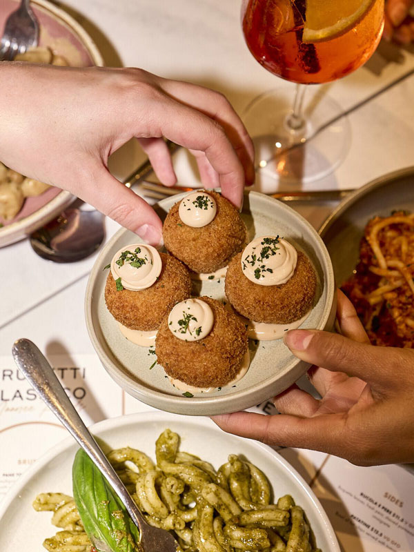 hands holding a plate of Italian food at Brunetti Classico, Carlton