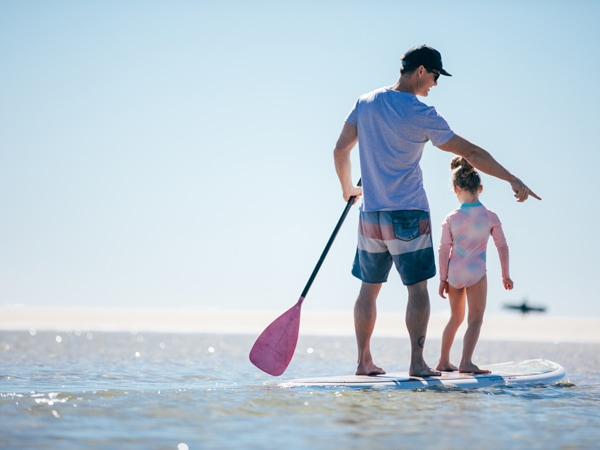 a father and child on a paddleboard at Currumbin Beach