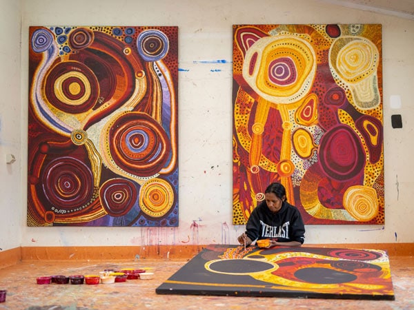 Emma Singer in the studio at Mimili Maku Arts in front of two major works. (Image: Meg Hansen and Mimili Maku Arts)