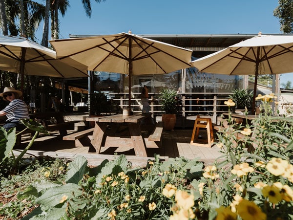 an al fresco dining setup with picnic tables and umbrellas at Federal Doma Cafe, Byron Bay