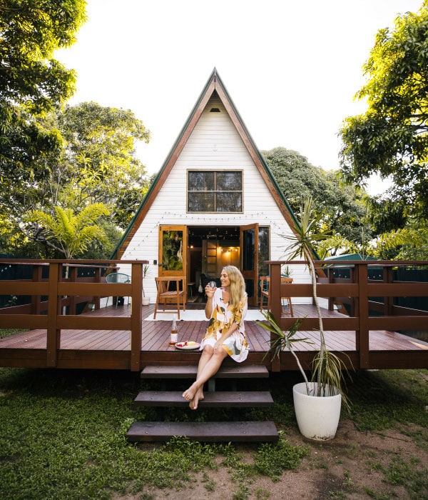 a lady sitting barefoot and holding a glass of wine in front of Maggie A-Frame