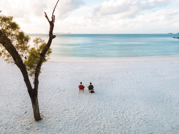 Couple sit on Whitehaven Beach