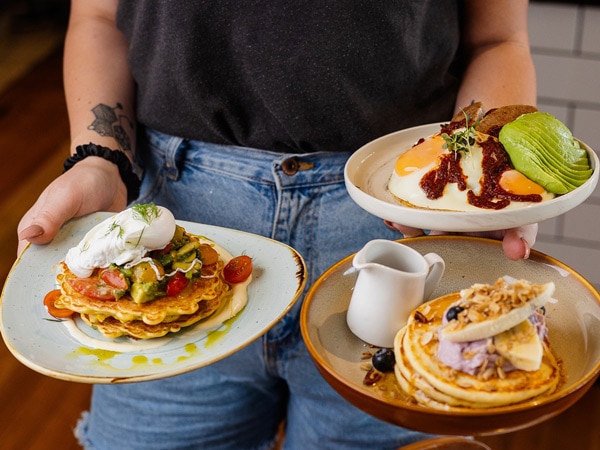 a woman holding plates of food at Penny Whistler, Kiama