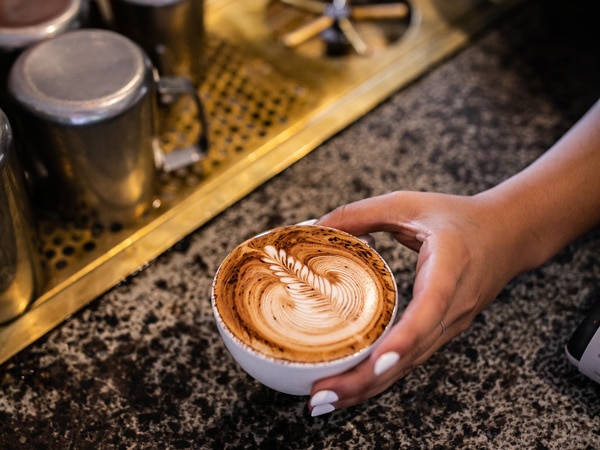 a hand holding a cup of coffee at The Hungry Monkey, Kiama