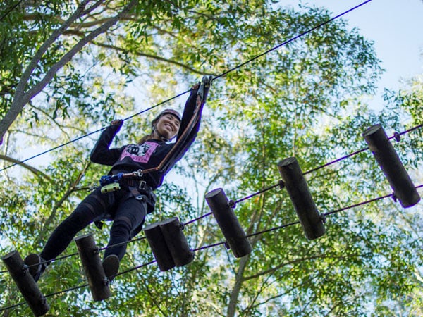 a woman crossing over an obstacle at the Treetop Adventure Park