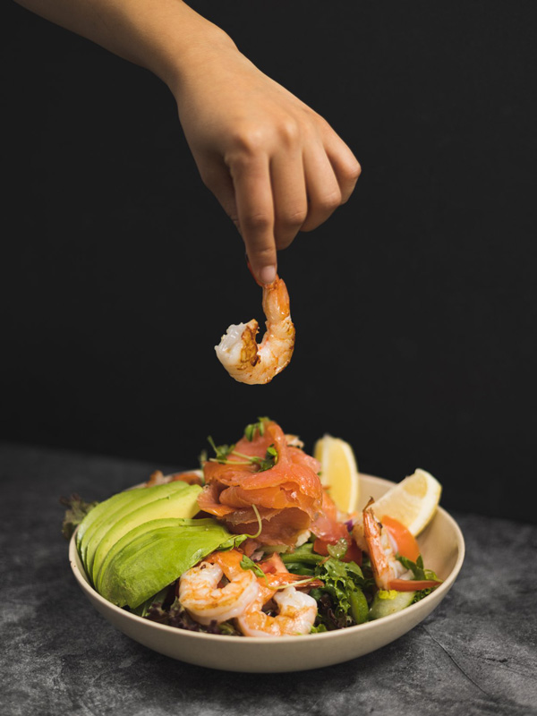 a hand holding a prawn over a dish at Saltwater Kiama