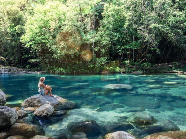a woman sitting on a rock at Mossman Gorge, Port Douglas