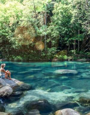 a woman sitting on a rock at Mossman Gorge, Port Douglas