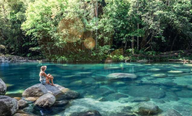 a woman sitting on a rock at Mossman Gorge, Port Douglas