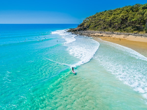 an aerial shot of a woman surfing at Tea Tree Bay, Noosa National Park