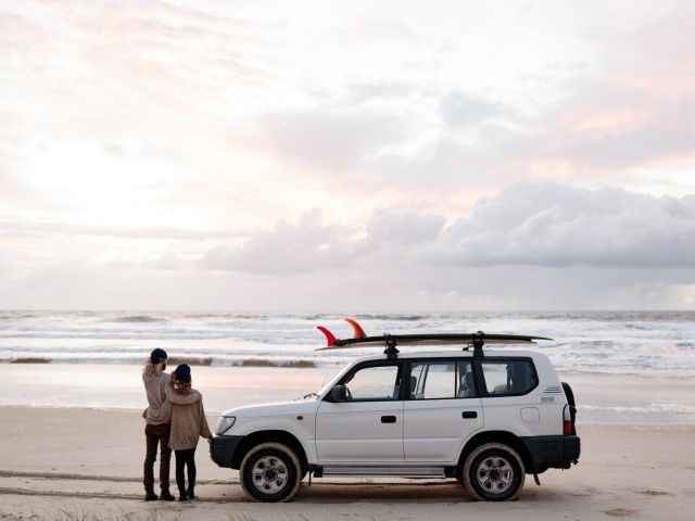 a couple standing beside a 4WD on Teewah Beach Camping Area