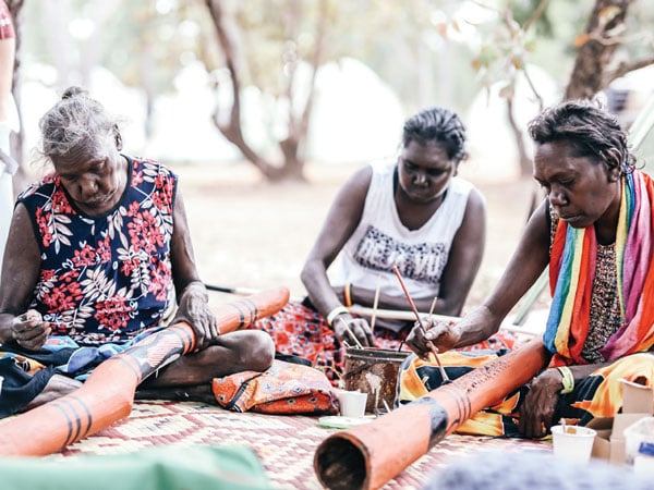 Women decorating yidakis at Garma