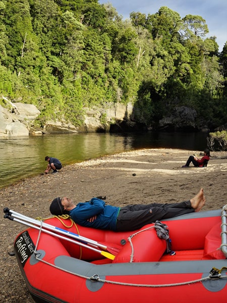 A man takes an afternoon nap on the raft beside the river