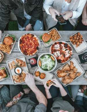 Overhead shot of table with-food-and group of people eating a diverse range of meals