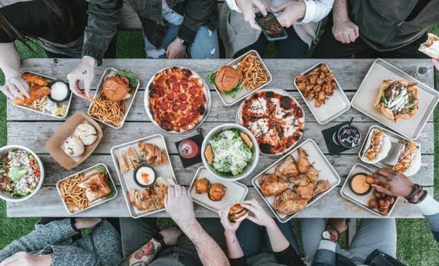 Overhead shot of table with-food-and group of people eating a diverse range of meals