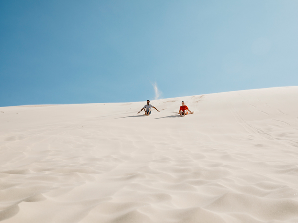 a couple enjoying sandboarding at Stockton SandDunes