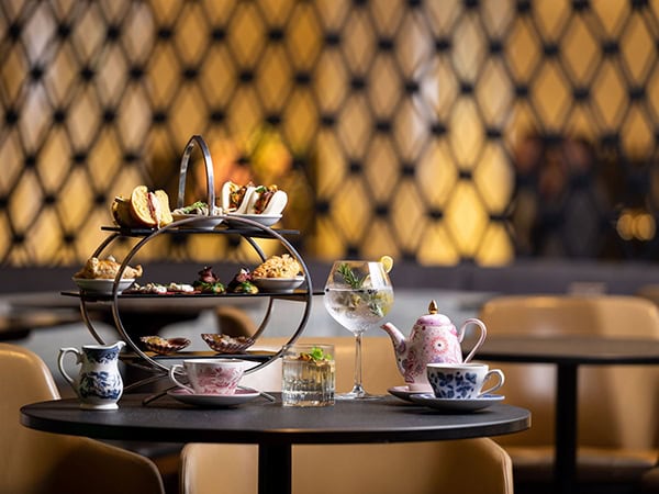 a picture of a decadent high tea with tea pots and a three-tiered tray full of treats at Hyatt Regency Sydney