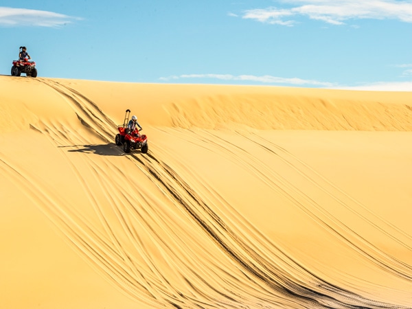 Couple enjoying a quad bike tour on the Stockton Sand Dunes with Sand Dune Adventures, Port Stephens